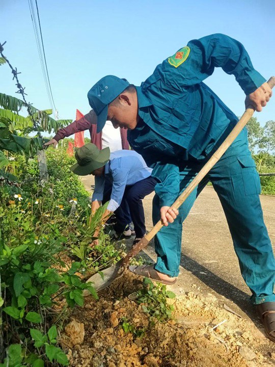 A person in blue uniform digging a hole in a gardenDescription automatically generated